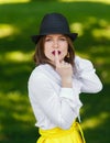 Young beautiful woman in hat shows hush sign