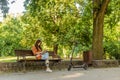 A young woman is sitting on a park bench with the book in her han Royalty Free Stock Photo