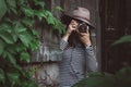 Young beautiful woman in hat is taking picture with old fashioned camera, outdoors Royalty Free Stock Photo