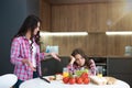 Young beautiful woman having an argument with her teen daughter during breakfast preparation in kitchen