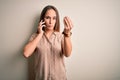 Young beautiful woman having conversation talking on the smartphone over white background Doing Italian gesture with hand and