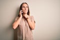 Young beautiful woman having conversation talking on the smartphone over white background Touching painful neck, sore throat for Royalty Free Stock Photo