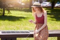 Young beautiful woman having rest in park, sitting on innovative bench and charging mobile device while checking her social Royalty Free Stock Photo