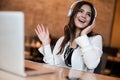 Young beautiful woman in headphones listening her favourite music from laptop while waiting her lunch in the cafe looking pleased