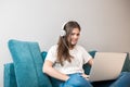 Young beautiful woman in headphones listening to her favourite music from laptop in the living room sitting on the sofa Royalty Free Stock Photo
