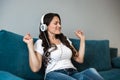 Young beautiful woman in headphones listening to her favourite music sitting on the sofa feeling happy Royalty Free Stock Photo