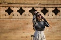 Young and beautiful woman, Hispanic, brown hair, with striped sweater, linen pants and sunglasses, waiting, talking on her cell Royalty Free Stock Photo