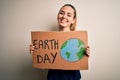 Young beautiful woman holding banner asking for earth and enviroment conservation with a happy face standing and smiling with a Royalty Free Stock Photo