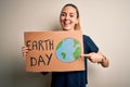 Young beautiful woman holding banner asking for earth and enviroment conservation very happy pointing with hand and finger Royalty Free Stock Photo