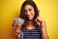 Young beautiful woman holding bowl with sunflowers seeds over isolated yellow background surprised with an idea or question Royalty Free Stock Photo