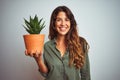 Young beautiful woman holding cactus pot over white isolated background with a happy face standing and smiling with a confident Royalty Free Stock Photo