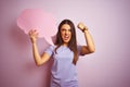 Young beautiful woman holding cloud speech bubble over isolated pink background annoyed and frustrated shouting with anger, crazy