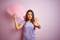 Young beautiful woman holding cloud speech bubble over isolated pink background with open hand doing stop sign with serious and