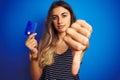 Young beautiful woman holding credit card over blue isolated background with angry face, negative sign showing dislike with thumbs Royalty Free Stock Photo
