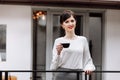 Young beautiful woman holding a cup of coffee or tea in cafe, restaurant. Brunette girl is drinking hot drinks, looking Royalty Free Stock Photo