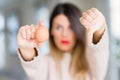 Young beautiful woman holding fresh egg at home with angry face, negative sign showing dislike with thumbs down, rejection concept Royalty Free Stock Photo