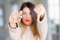 Young beautiful woman holding fresh quail egg at home with angry face, negative sign showing dislike with thumbs down, rejection Royalty Free Stock Photo