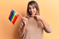 Young beautiful woman holding lgtbq flag smiling happy pointing with hand and finger