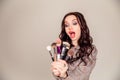 Young beautiful woman holding makeup brushes in her hands and posing on grey background at studio Royalty Free Stock Photo