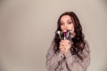 Young beautiful woman holding makeup brushes in her hands and posing on grey background at studio Royalty Free Stock Photo