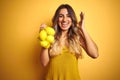 Young beautiful woman holding net of lemons over yellow isolated background very happy and excited, winner expression celebrating Royalty Free Stock Photo