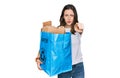 Young beautiful woman holding recycling wastebasket with paper and cardboard pointing with finger to the camera and to you, Royalty Free Stock Photo