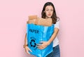 Young beautiful woman holding recycling wastebasket with paper and cardboard thinking attitude and sober expression looking self Royalty Free Stock Photo