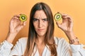 Young beautiful woman holding slice of kiwi over eyes skeptic and nervous, frowning upset because of problem Royalty Free Stock Photo