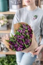 Young beautiful woman holding a spring bouquet of purple tulips in her hand. Bunch of fresh cut spring flowers in female Royalty Free Stock Photo