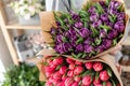 Young beautiful woman holding a spring bouquet of red and purple tulips in her hand. Bunch of fresh cut spring flowers