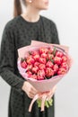 Young beautiful woman holding a spring bouquet of red tulips in her hand. Bunch of fresh cut spring flowers in female Royalty Free Stock Photo