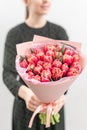 Young beautiful woman holding a spring bouquet of red tulips in her hand. Bunch of fresh cut spring flowers in female Royalty Free Stock Photo