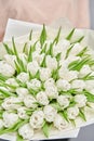 Young beautiful woman holding a spring bouquet of white tulips in her hand. Bunch of fresh cut spring flowers in female
