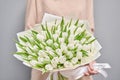 Young beautiful woman holding a spring bouquet of white tulips in her hand. Bunch of fresh cut spring flowers in female Royalty Free Stock Photo