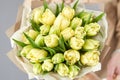 Young beautiful woman holding a spring bouquet of yellow tulips in her hand. Bunch of fresh cut spring flowers in female