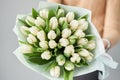 Young beautiful woman holding a spring bouquet of yellow tulips in her hand. Bunch of fresh cut spring flowers in female Royalty Free Stock Photo