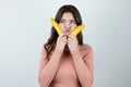 Young beautiful woman holding two fresh bananas near face looking doubtful being on diet isolated white background Royalty Free Stock Photo