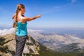 Young and beautiful woman holds child in hands and points fingers at the mountains. Montenegro, Lovcen national Park