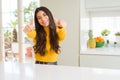 Young beautiful woman at home on white table approving doing positive gesture with hand, thumbs up smiling and happy for success Royalty Free Stock Photo