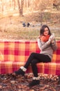 Young beautiful woman in a knitted sweater sitting on a bench in an autumn park Royalty Free Stock Photo