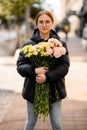 Young beautiful woman with large bouquet of yellow, pink, lemon and milk colors carnations in hands. Royalty Free Stock Photo