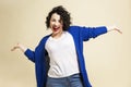 Young beautiful woman is laughing and dancing. Bright brunette with curly hair and red lipstick in jeans