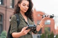 Young beautiful woman launching drone quadcopter at urban background. cityscape. modern device