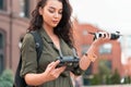 Young beautiful woman launching drone quadcopter at urban background. cityscape. modern device