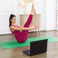 Young beautiful woman leading a healthy lifestyle and practicing yoga, watching online lessons and doing Paripurna Navasana Royalty Free Stock Photo