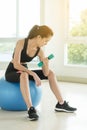 Young beautiful woman lift dumbbell sit on ball