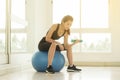 Young beautiful woman lift dumbbell sit on ball