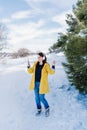 young beautiful woman listening to music on mobile phone and headset in the snow. wearing yellow coat, winter lifestyle Royalty Free Stock Photo