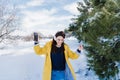 young beautiful woman listening to music on mobile phone and headset in the snow. wearing yellow coat, winter lifestyle Royalty Free Stock Photo