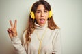 Young beautiful woman listening to music using headphones over white isolated background smiling with happy face winking at the Royalty Free Stock Photo